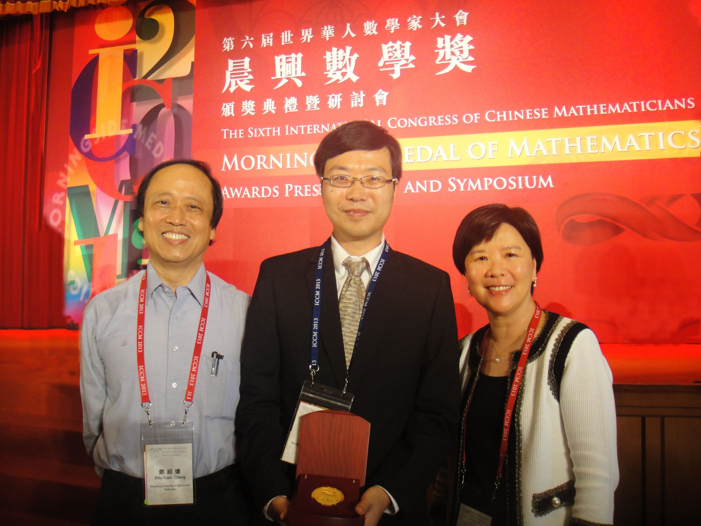 理 學 院 院 長 葉 玉 如 教 授 （ 右 ） 、 數 學 系 鄭 紹 遠 講 座 教授 （ 左 ） 恭 賀 何 旭 華 教 授 獲 頒 晨 興 數 學 金 獎 。	