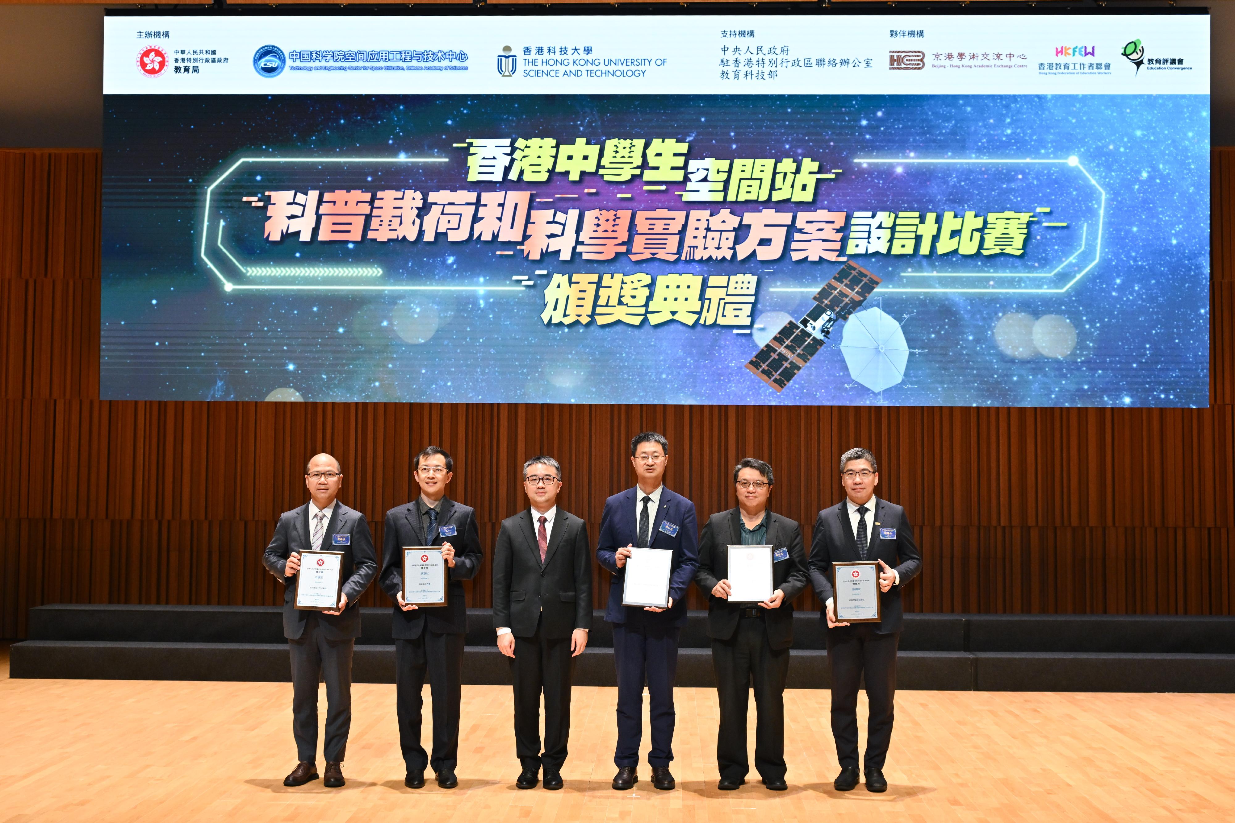 教育局在科大举办香港中学生空间站科普载荷和科学实验方案设计比赛颁奖典礼。图示教育局副局长施俊辉博士（左三）与嘉宾合照（左起：香港教育工作者联会主席黄锦良、科大物理系教授王一、施俊辉博士、中国科学院空间应用工程与技术中心副总师钟红恩博士、教育评议会主席蔡世鸿及京港学术交流中心总裁徐海山）。